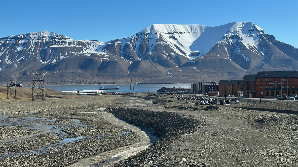 Bilde fra Svalbard som viser fjell med litt snø på, og sol